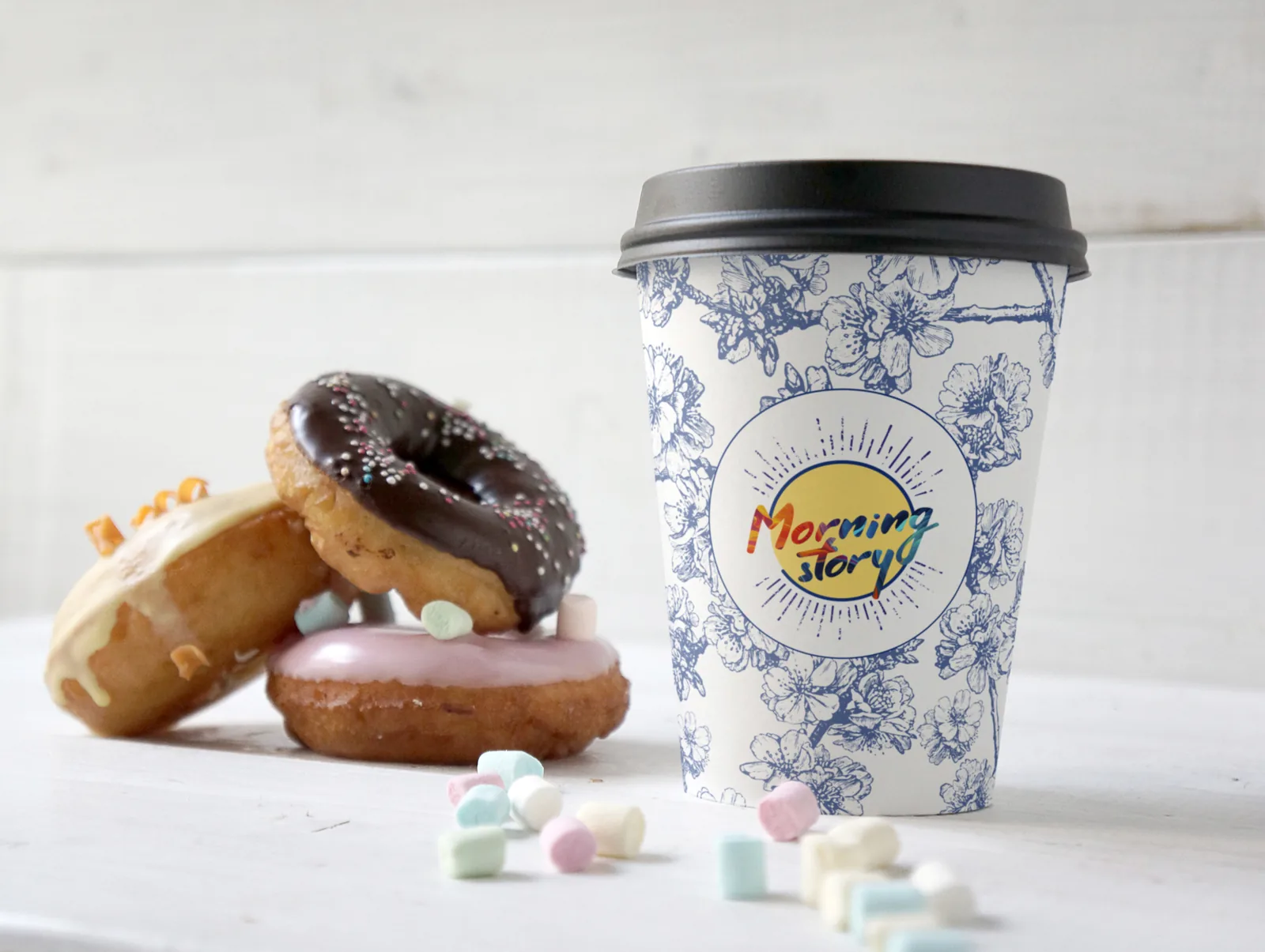 A floral cup beside a stack of doughnuts